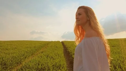 Happy woman with long hair on summer green field at sunset slow motion Stock Footage