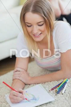 Happy woman lying on floor sketching on paper Stock Photos