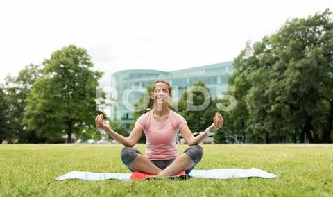 Happy woman meditating in summer park Stock Photos