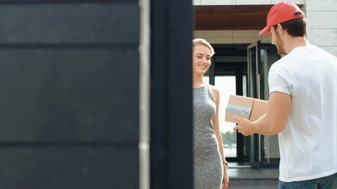 Happy woman meeting delivery man with paper box. Smiling woman receiving parcel Stock Footage