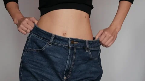 Happy woman in the process of trying on old jeans. Stock Footage 306255343