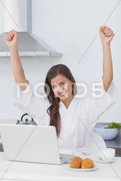 Happy woman raising arms while using a laptop Stock Photos