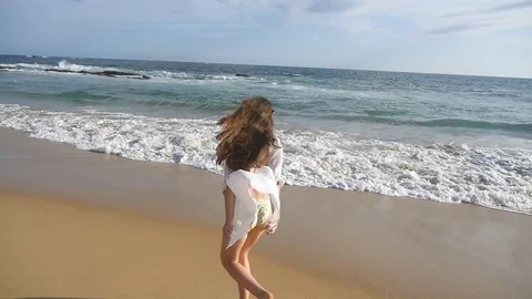 Happy woman running and spinning on the beach near the ocean. Young beautiful Stock Footage