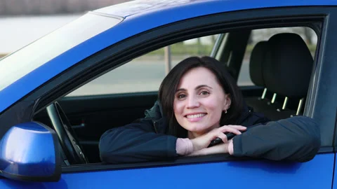 Happy woman sitting in the blue car, smiling and enjoying the spring Stock Footage