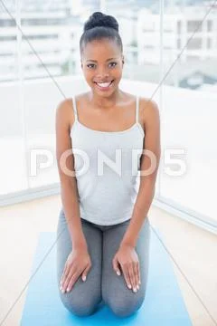 Happy woman sitting on blue exercise mat Stock Photos