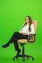 The happy woman sitting on the chair on the green background Photo