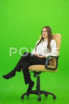 The happy woman sitting on the chair on the green background Stock Photos
