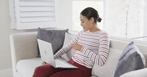 Happy woman sitting on sofa using laptop for online shopping, slow motion Stock Footage 340068490