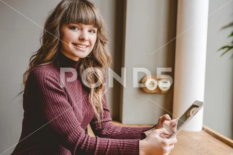 The happy woman sitting with a tablet at the restaurant table Stock Photos