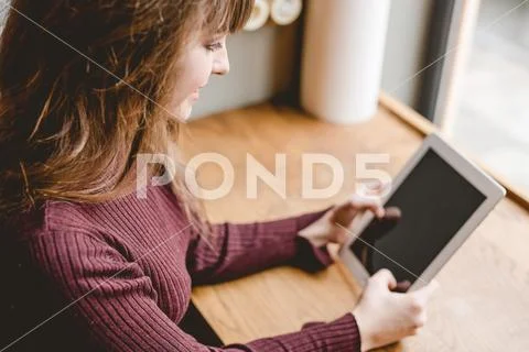 The happy woman sitting with a tablet at the restaurant table Stock Photos