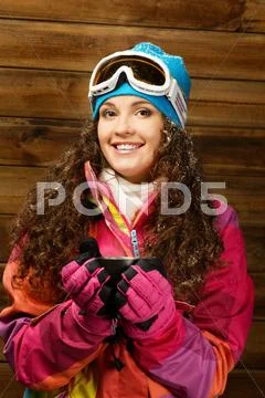 Happy woman in ski wear with cup of a hot drink against wooden wall Stock Photos