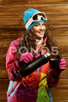 Happy woman in ski wear with thermos against wooden wall Stock Photos