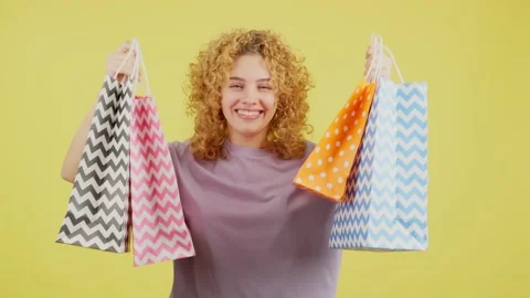 Happy woman smiling at the camera while showing shopping bags Vídeo Stock 234856122