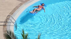 Two Women Are Relaxing In Pool On Air Mattress Are Drinking