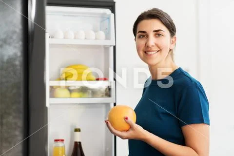 Happy woman taking food from fridge at home Stock Photos