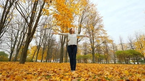 Happy woman throwing up fallen maple leaves Stock Footage 97388901