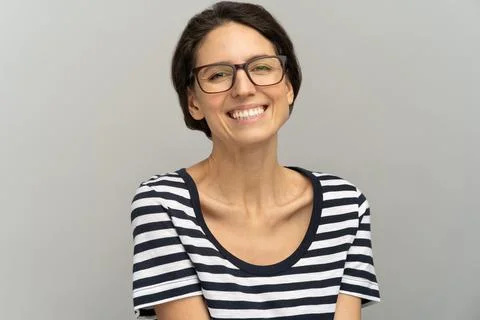 Happy woman with toothy smile wear glasses and stripped t-shirt looking at Stock Photos