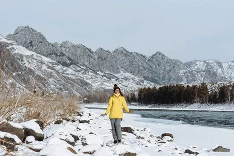 Happy woman traveler in winter clothes on the background of mountains and riv Stock Photos