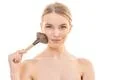 The happy woman using a cosmetic brush on the white background Photo
