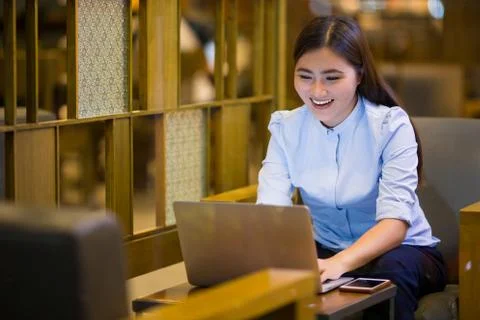 Happy woman using laptop in cafe at night time Stock Photos