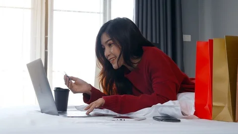 Happy woman using laptop computer for online shopping with credit card on a bed Stock Footage 97369998