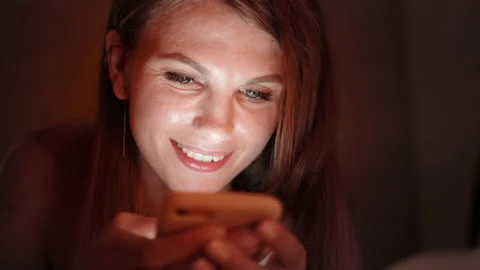 Happy woman using smartphone while relaxing on bed Stock Footage 165602044