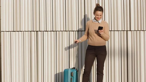 Happy Woman Using Smartphone While Waiting to Board Видео 332451079