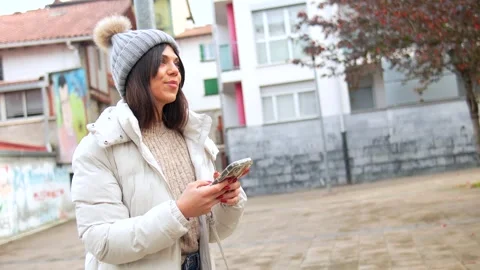 Happy woman in warm clothes using phone in the city Stock Footage 295481833