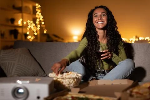 Happy Woman Watching Movie Using Home Cinema Projector Sitting Indoors Stock Photos