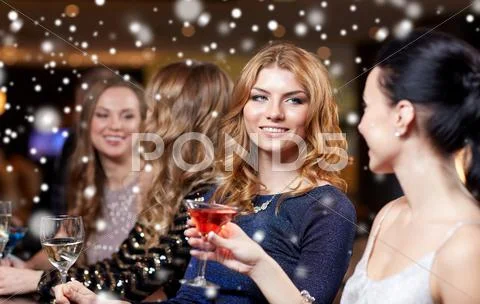 Happy women with drinks at night club over snow Stock Photos