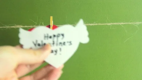 Happy Women's Day. Hands fixing a white paper heart with wings on a cord with a Stock Footage 73309327