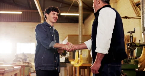 Happy, woodworker and men in workshop with handshake, training feedback and Stock Footage 340620713
