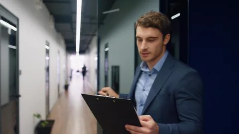 Happy worker checking papers on clipboard. Office mentor making notes walking Stock Photos