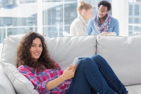 Happy worker using tablet pc while laying on a couch Stock-Fotos