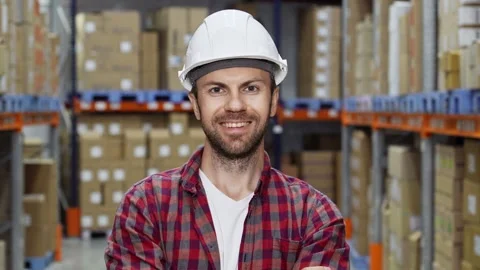 Happy worker in white helmet looking at camera and smiling in warehouse Video stock 285311537