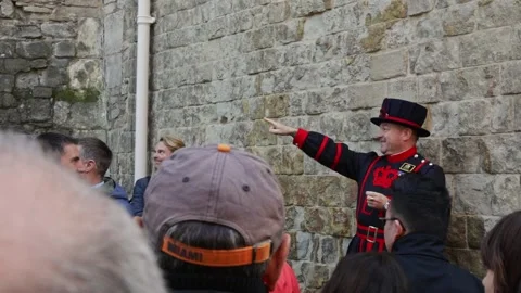 Happy yeoman tour guide talking to tourist while standing near Tower of Stock Footage 214848667