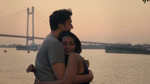 Happy young affectionate couple hugging each other against the evening sunset. Video stock 268730599