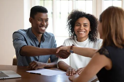 Happy young african american clients shaking hands with financial advisor. Stock Photos