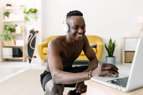 Happy young african man searching training video fitness program on laptop Stock Photos