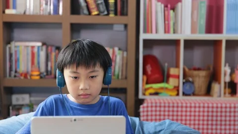 Happy young asian boy while connection on video call at home speaking lookin Stock Footage 129534506