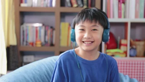 Happy young asian boy while connection on blue headphones Stock Footage 198475258