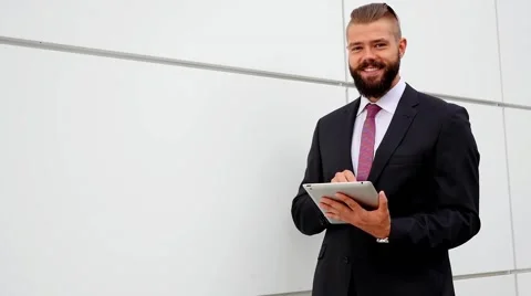 Happy young bearded businessman using his tablet pc. Outdoor photo Stock Footage 56526446