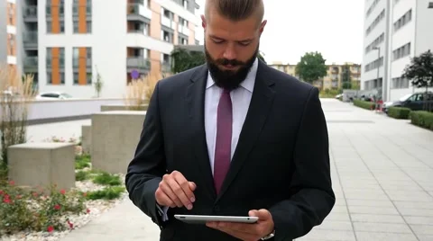 Happy young bearded businessman using his tablet pc. Outdoor photo Stock Footage 60944811