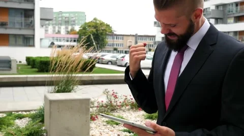 Happy young bearded businessman using his tablet pc. Outdoor photo. Stock Footage 60945195