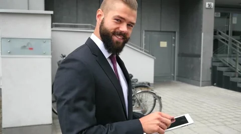 Happy young bearded businessman using his tablet pc. Outdoor photo Stock Footage 60945216