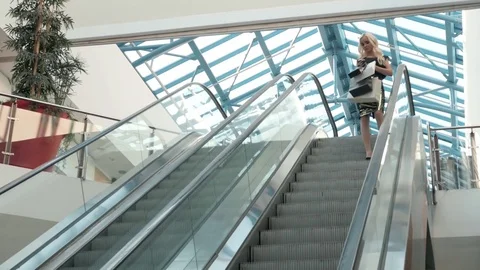 Happy young blonde woman using cell phone at a shopping center, beautiful Stock Footage