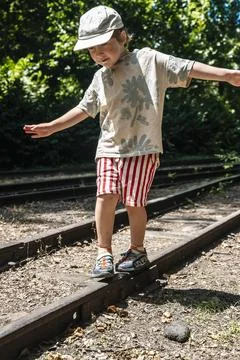 Happy young boy balancing on old railway tracks in forest Stockfoto's