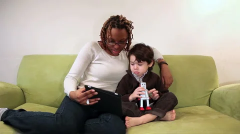 Happy young boy on couch with young women reading a story from an iPad 動画素材 1071028