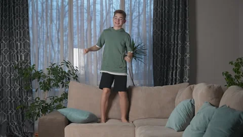 Happy young boy dancing on sofa, celebrating a win, having fun in living room. Stock Footage 271147782