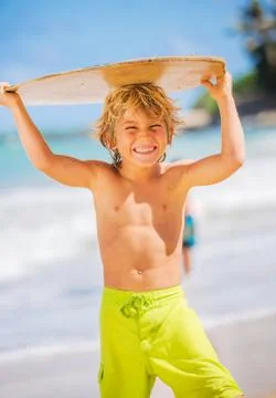 Happy young boy having fun at the beach on vacation, with skimboard Stock Photos